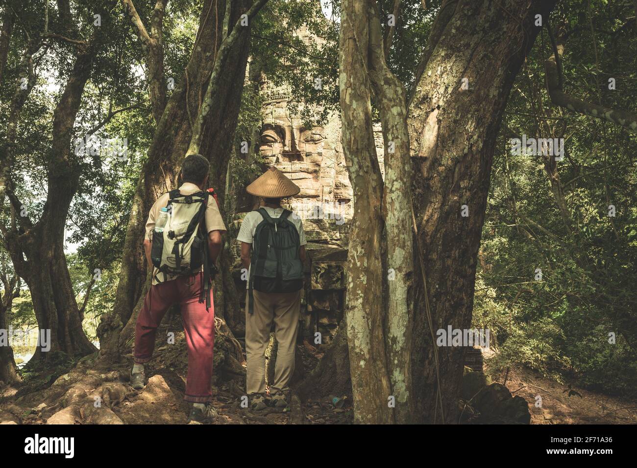 Couple regardant des visages de pierre dans la jungle, Bayon Temple Angkor Thom. Le concept de méditation du bouddhisme, destination de voyage de renommée mondiale, le tourisme au Cambodge. Banque D'Images