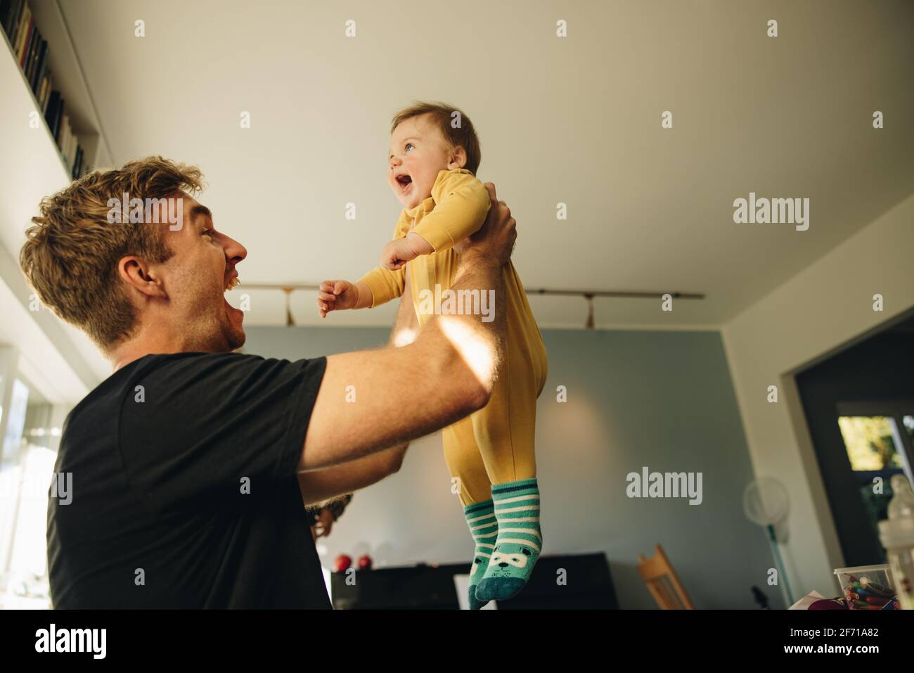 Homme excité tenant son bébé garçon. Homme jouant avec son nouveau-né à la maison à la maison. Banque D'Images