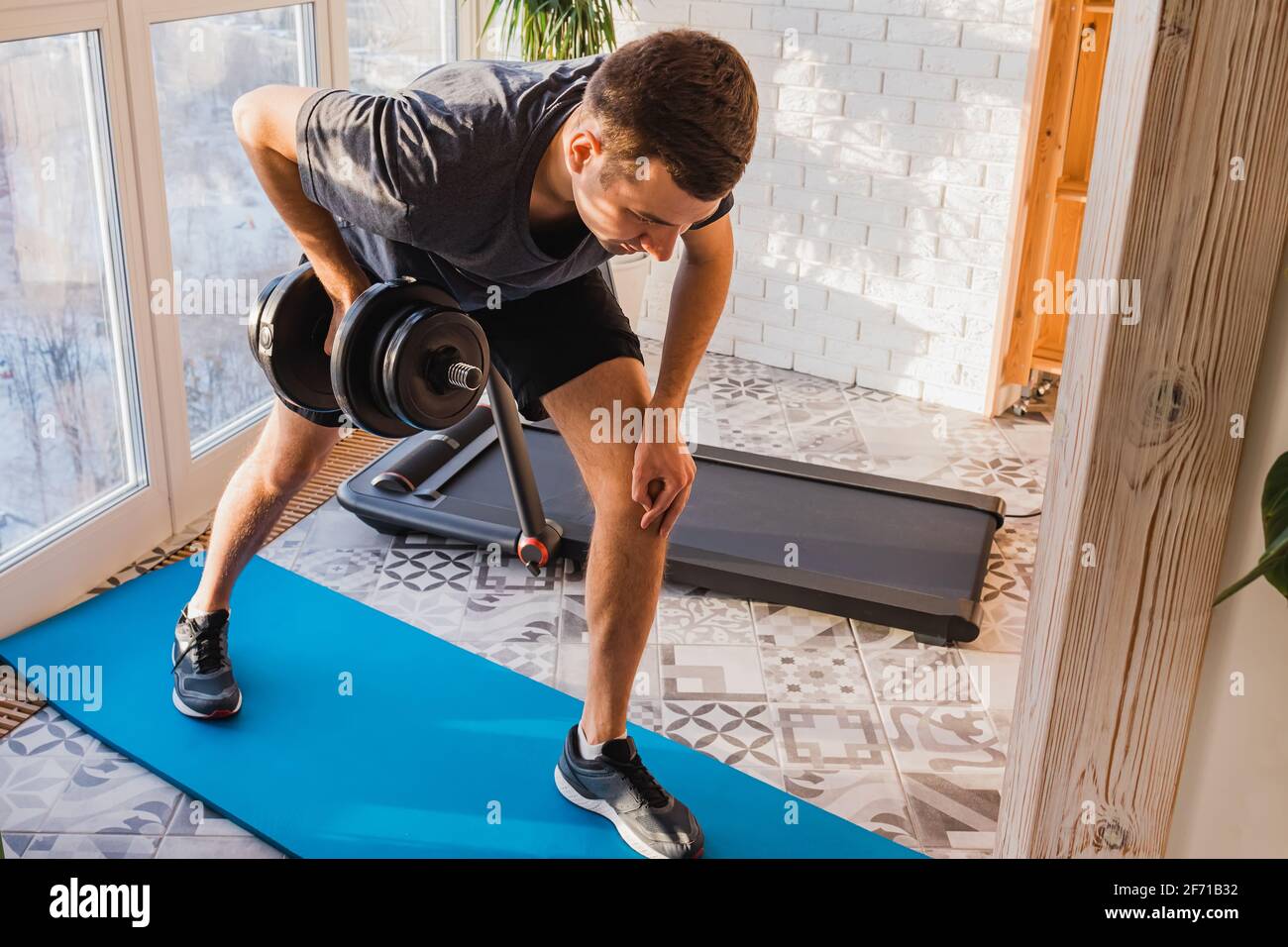 Homme athlétique faisant un exercice de dumbell de rangée de bras Banque D'Images