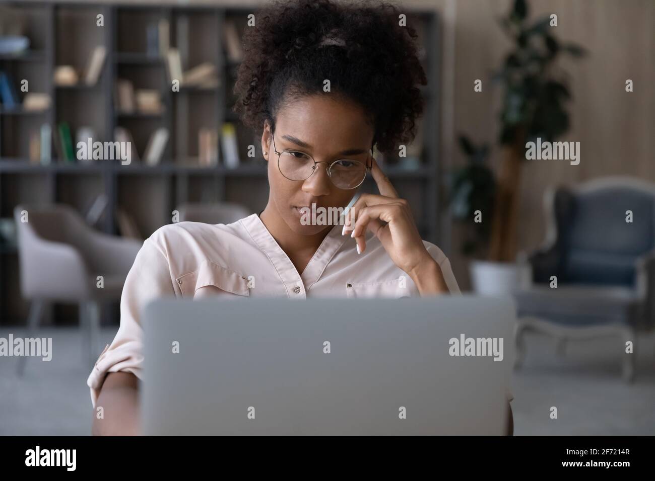 Une femme biraciale pensive travaille sur la pensée d'un ordinateur portable Banque D'Images