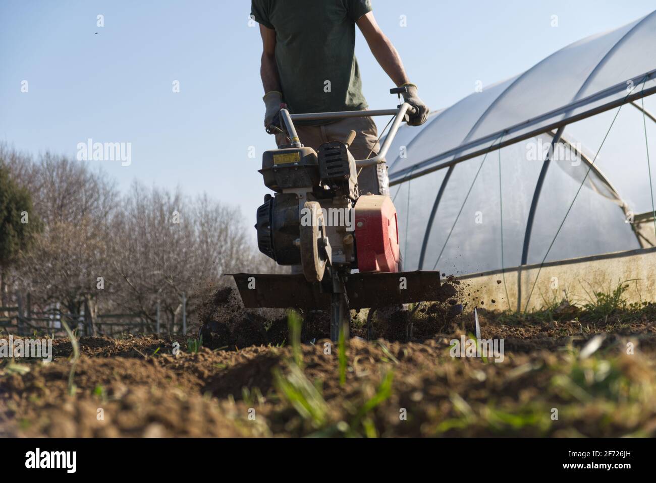 Un agriculteur prépare le terrain pour le potager d'été avec un couteau Banque D'Images