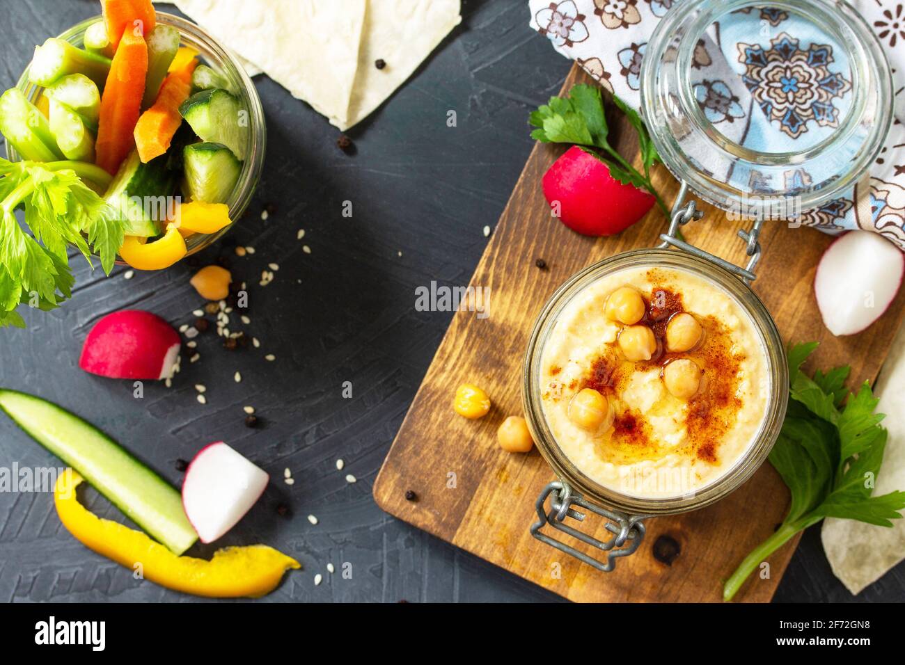 Cuisine arabe. Houmous du Moyen-Orient avec en-cas. Trempez le houmous avec des bâtonnets de légumes frais sur un comptoir en pierre foncée. Vue de dessus. Pose à plat. Copier l'espace. Banque D'Images
