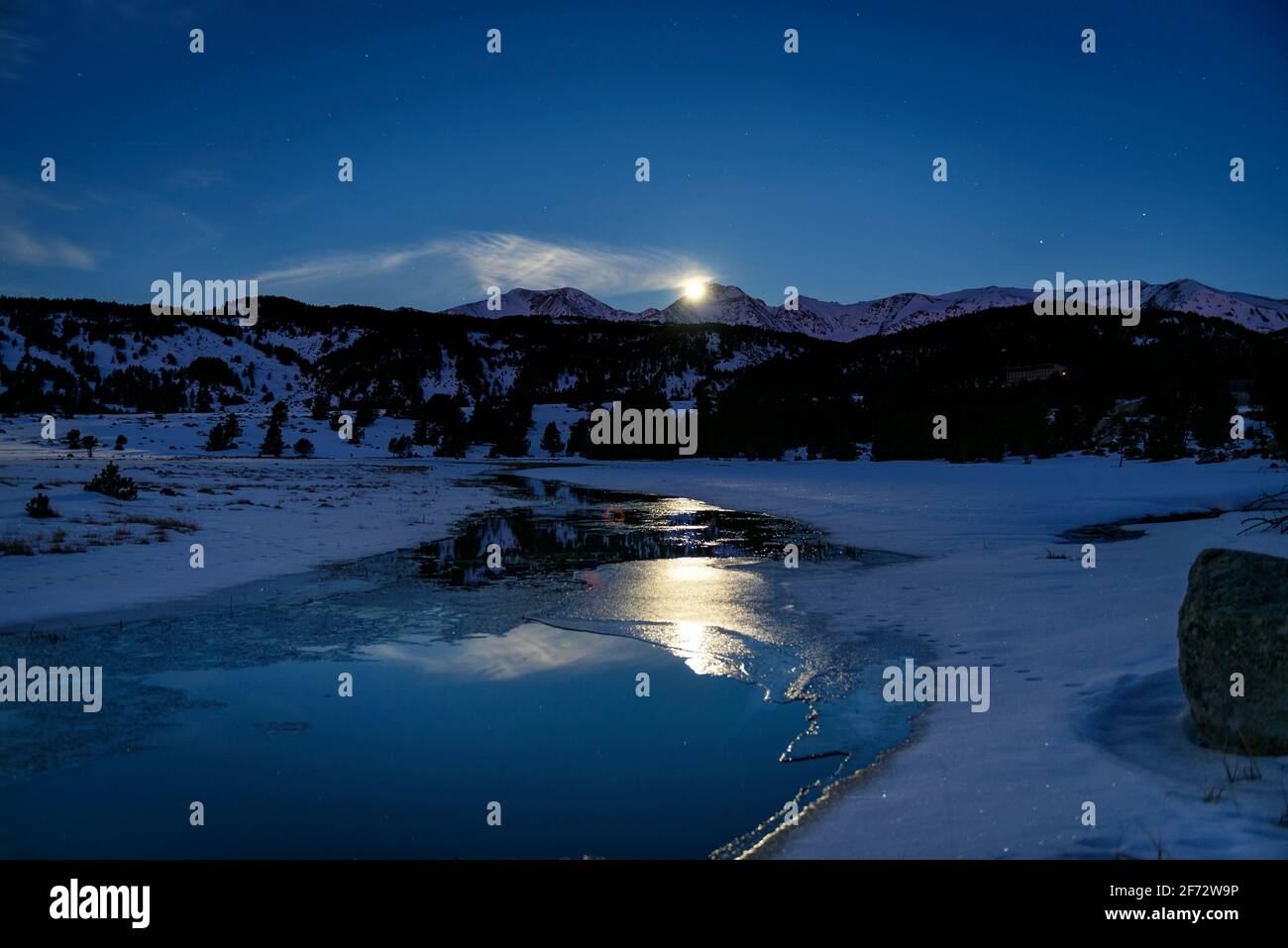 Des vues nocturnes d'hiver sur le lac de Bulloseta et la Lune derrière le pic de Carlit (Pyrénées-Orientales, Occitania, France) Banque D'Images