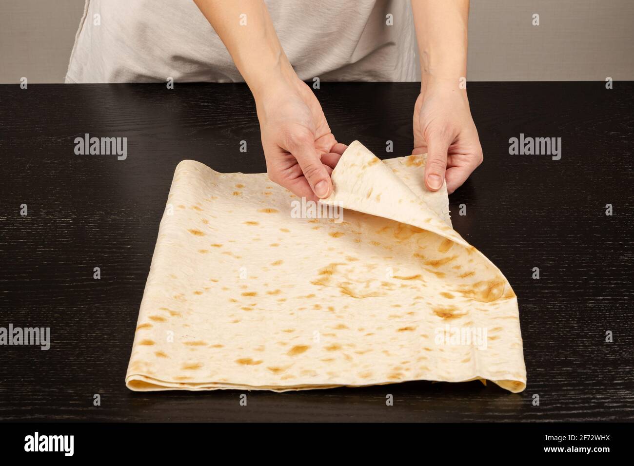 les mains des femmes ont préparé du pain pita frais pour faire du shawarma sur le fond d'une table en bois noir gros plan Banque D'Images