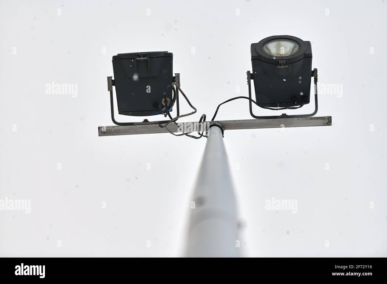 Puissante lumière LED sur poteau métallique en aluminium, fond ciel gris nuageux avec flocons de neige. Éclairage DE rue À LED, feu de stationnement. Source de lumière moderne. Banque D'Images