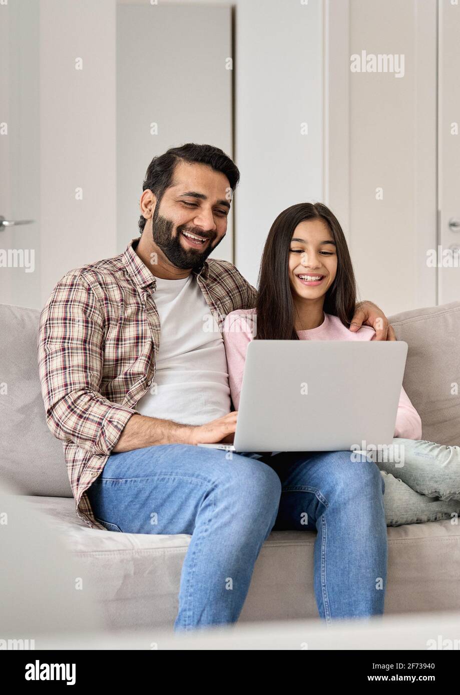 Papa indien heureux avec une fille adolescente s'amusant à utiliser un ordinateur portable à la maison. Banque D'Images