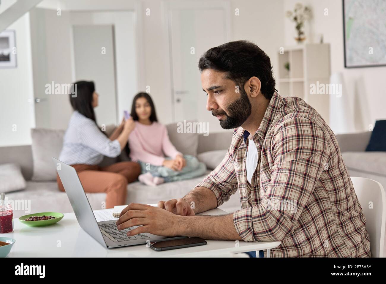 Jeune homme indien père travaillant à distance en ligne à partir du bureau à domicile avec la famille. Banque D'Images