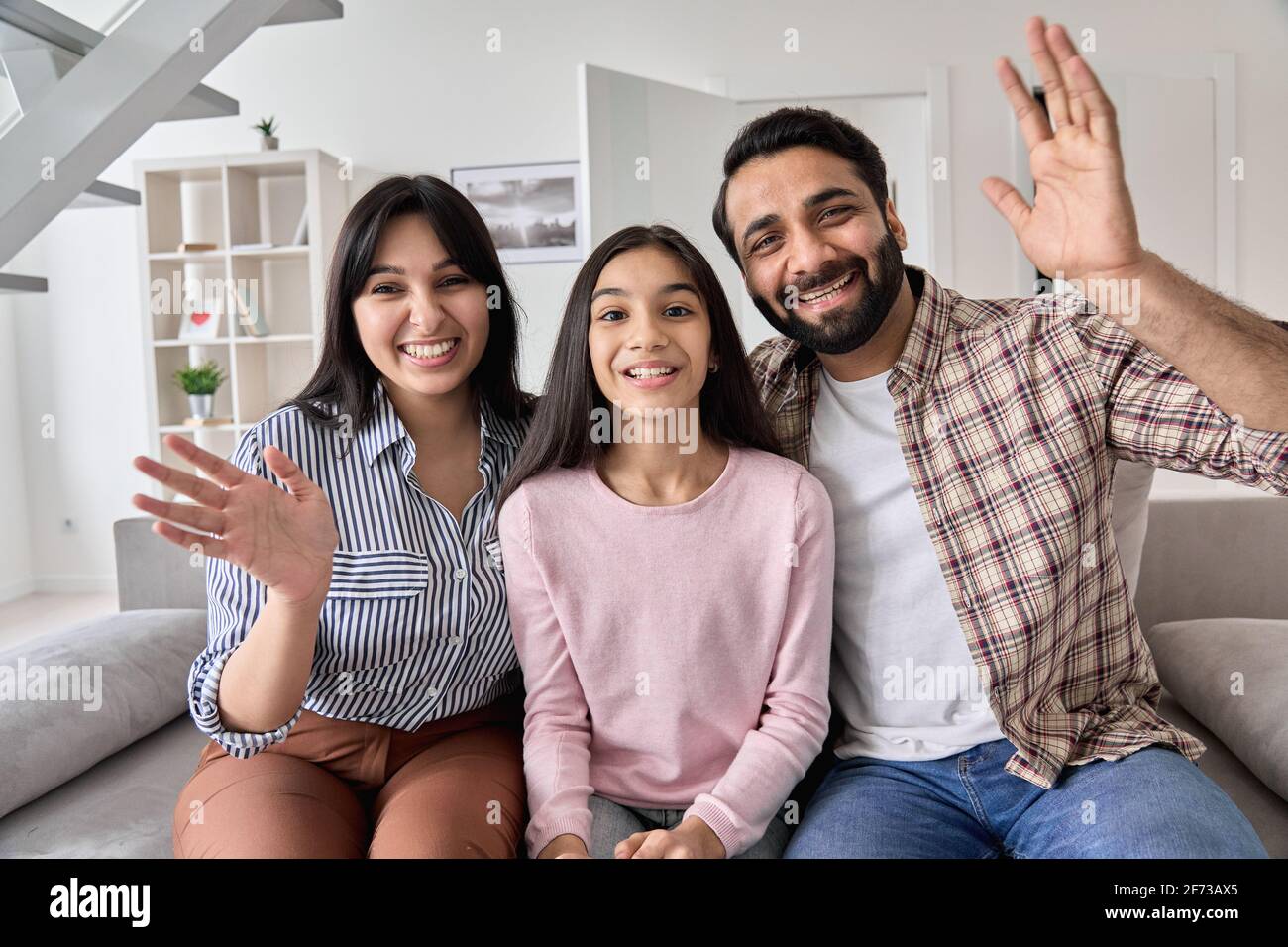 Un couple indien heureux et une fille adolescente agitant les mains regardant l'appareil photo. Banque D'Images