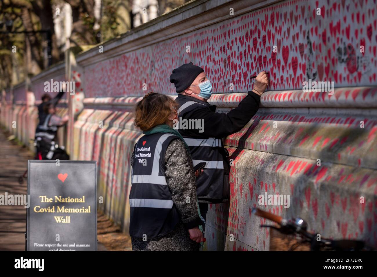 Londres, Royaume-Uni. 4 avril 2021. Les volontaires tirent le cœur le dimanche de Pâques sur un mur à Lambeth, près de la Tamise, chaque cœur représentant une personne décédée pendant la pandémie de coronavirus au Royaume-Uni. Appelé le mur commémoratif national Covid, il a été créé par le groupe Covid-19 Bereaved Families for Justice avec des travaux qui débutent il y a une semaine et s'étendra sur un demi-mile à la fin. Credit: Stephen Chung / Alamy Live News Banque D'Images