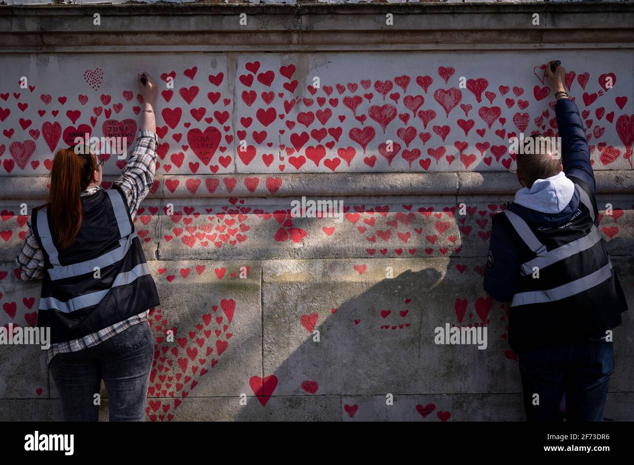 Londres, Royaume-Uni. 4 avril 2021. Les volontaires tirent le cœur le dimanche de Pâques sur un mur à Lambeth, près de la Tamise, chaque cœur représentant une personne décédée pendant la pandémie de coronavirus au Royaume-Uni. Appelé le mur commémoratif national Covid, il a été créé par le groupe Covid-19 Bereaved Families for Justice avec des travaux qui débutent il y a une semaine et s'étendra sur un demi-mile à la fin. Credit: Stephen Chung / Alamy Live News Banque D'Images