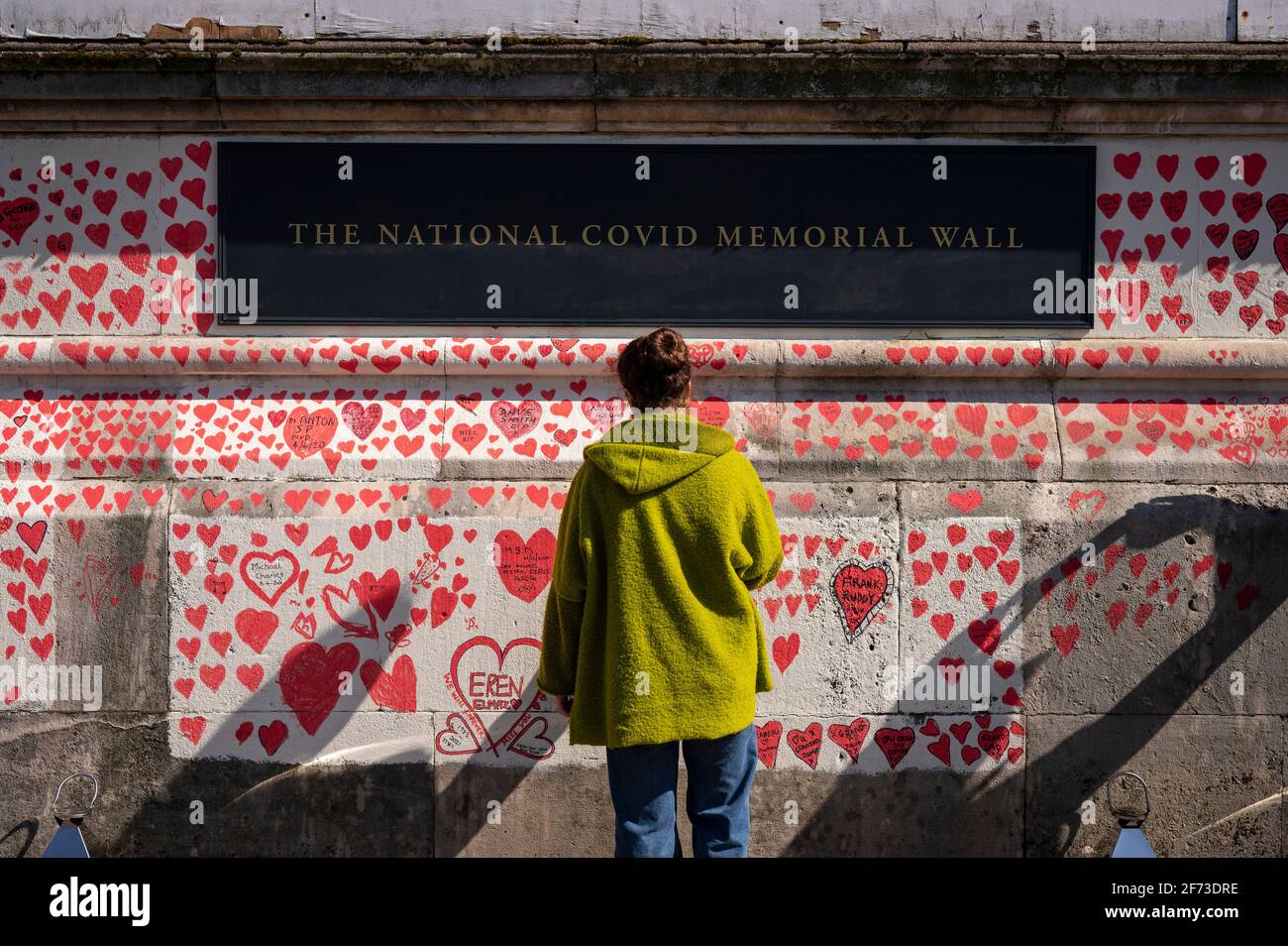 Londres, Royaume-Uni. 4 avril 2021. Un volontaire tire les coeurs le dimanche de Pâques sur un mur à Lambeth près de la Tamise, chaque cœur représentant une personne décédée pendant la pandémie de coronavirus au Royaume-Uni. Appelé le mur commémoratif national Covid, il a été créé par le groupe Covid-19 Bereaved Families for Justice avec des travaux qui débutent il y a une semaine et s'étendra sur un demi-mile à la fin. Credit: Stephen Chung / Alamy Live News Banque D'Images