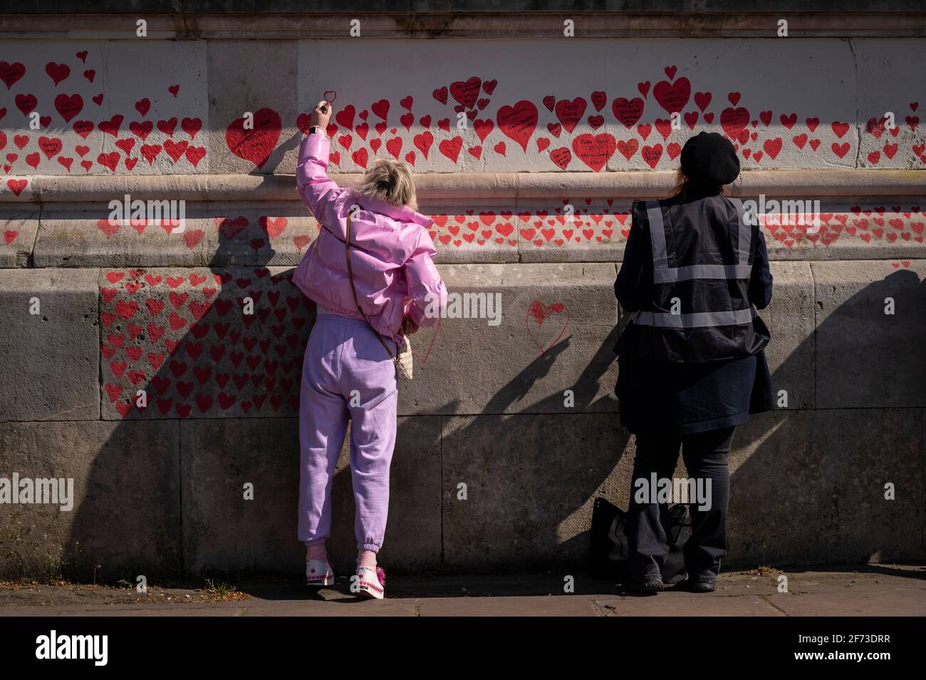 Londres, Royaume-Uni. 4 avril 2021. Les volontaires tirent le cœur le dimanche de Pâques sur un mur à Lambeth, près de la Tamise, chaque cœur représentant une personne décédée pendant la pandémie de coronavirus au Royaume-Uni. Appelé le mur commémoratif national Covid, il a été créé par le groupe Covid-19 Bereaved Families for Justice avec des travaux qui débutent il y a une semaine et s'étendra sur un demi-mile à la fin. Credit: Stephen Chung / Alamy Live News Banque D'Images