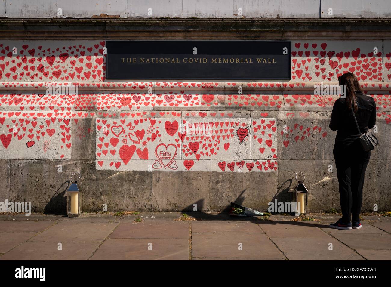 Londres, Royaume-Uni. 4 avril 2021. Une femme regarde les coeurs le dimanche de Pâques sur un mur à Lambeth près de la Tamise, chaque cœur représentant une personne décédée pendant la pandémie de coronavirus au Royaume-Uni. Appelé le mur commémoratif national Covid, il a été créé par le groupe Covid-19 Bereaved Families for Justice avec des travaux qui débutent il y a une semaine et s'étendra sur un demi-mile à la fin. Credit: Stephen Chung / Alamy Live News Banque D'Images