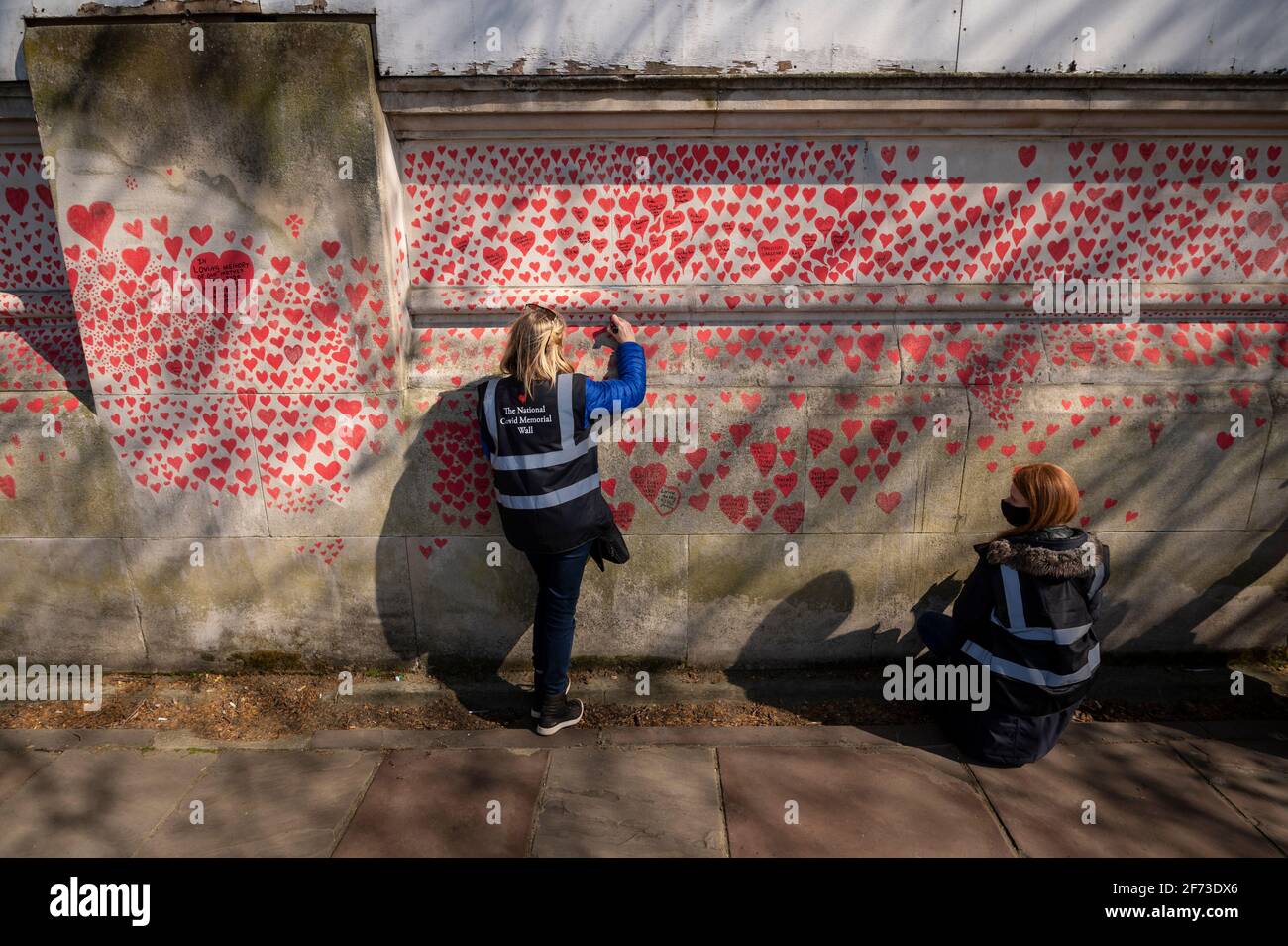 Londres, Royaume-Uni. 4 avril 2021. Les volontaires tirent le cœur le dimanche de Pâques sur un mur à Lambeth, près de la Tamise, chaque cœur représentant une personne décédée pendant la pandémie de coronavirus au Royaume-Uni. Appelé le mur commémoratif national Covid, il a été créé par le groupe Covid-19 Bereaved Families for Justice avec des travaux qui débutent il y a une semaine et s'étendra sur un demi-mile à la fin. Credit: Stephen Chung / Alamy Live News Banque D'Images