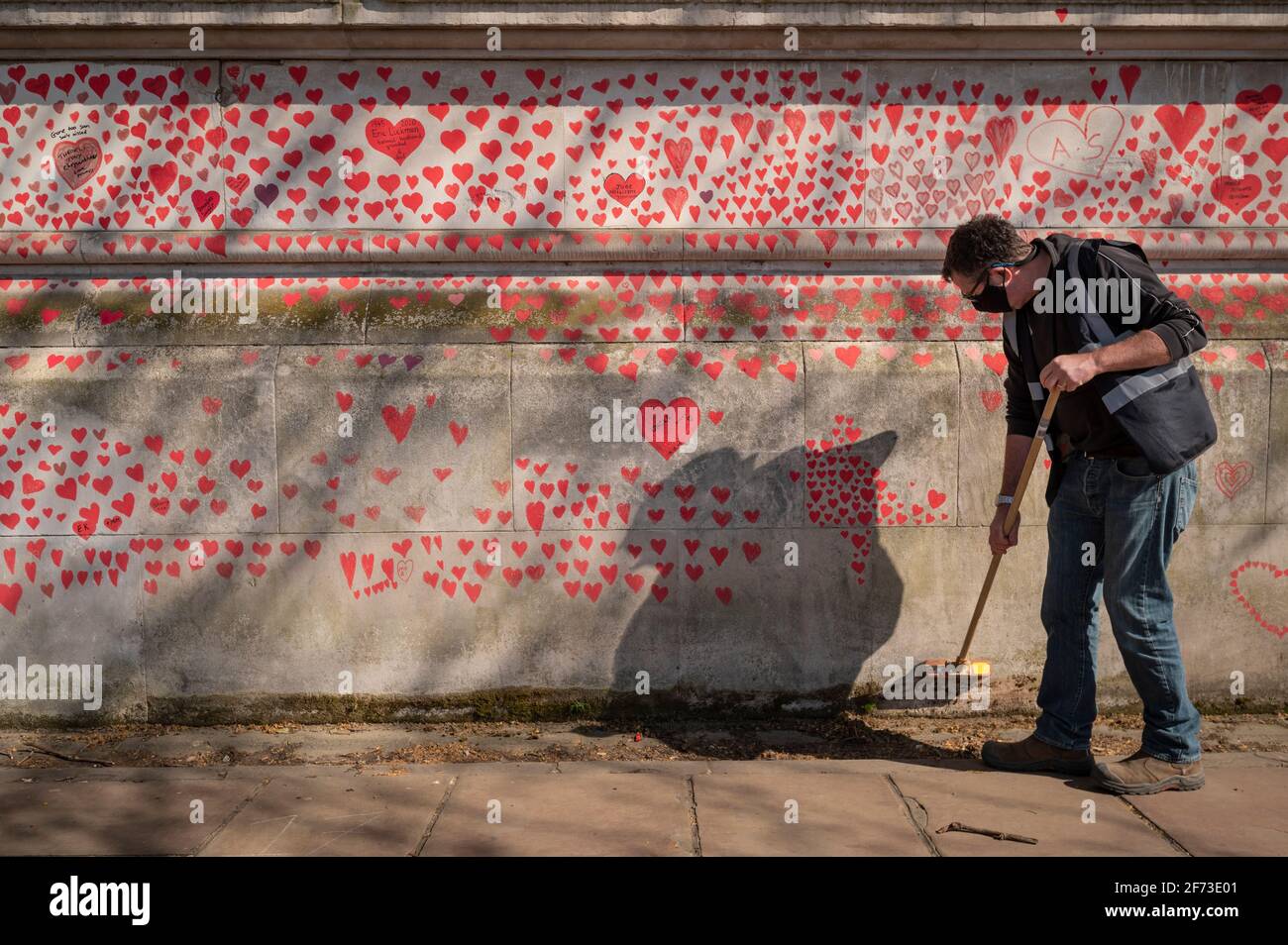 Londres, Royaume-Uni. 4 avril 2021. Un membre du personnel effectue des travaux d’entretien le dimanche de Pâques sur un cœur de mur à Lambeth, près de la Tamise, chaque cœur représentant une personne décédée pendant la pandémie de coronavirus au Royaume-Uni. Appelé le mur commémoratif national Covid, il a été créé par le groupe Covid-19 Bereaved Families for Justice avec des travaux qui débutent il y a une semaine et s'étendra sur un demi-mile à la fin. Credit: Stephen Chung / Alamy Live News Banque D'Images