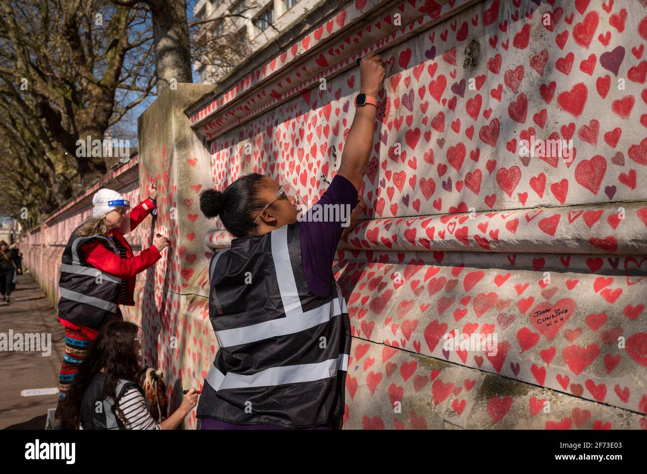 Londres, Royaume-Uni. 4 avril 2021. Les volontaires tirent le cœur le dimanche de Pâques sur un mur à Lambeth, près de la Tamise, chaque cœur représentant une personne décédée pendant la pandémie de coronavirus au Royaume-Uni. Appelé le mur commémoratif national Covid, il a été créé par le groupe Covid-19 Bereaved Families for Justice avec des travaux qui débutent il y a une semaine et s'étendra sur un demi-mile à la fin. Credit: Stephen Chung / Alamy Live News Banque D'Images