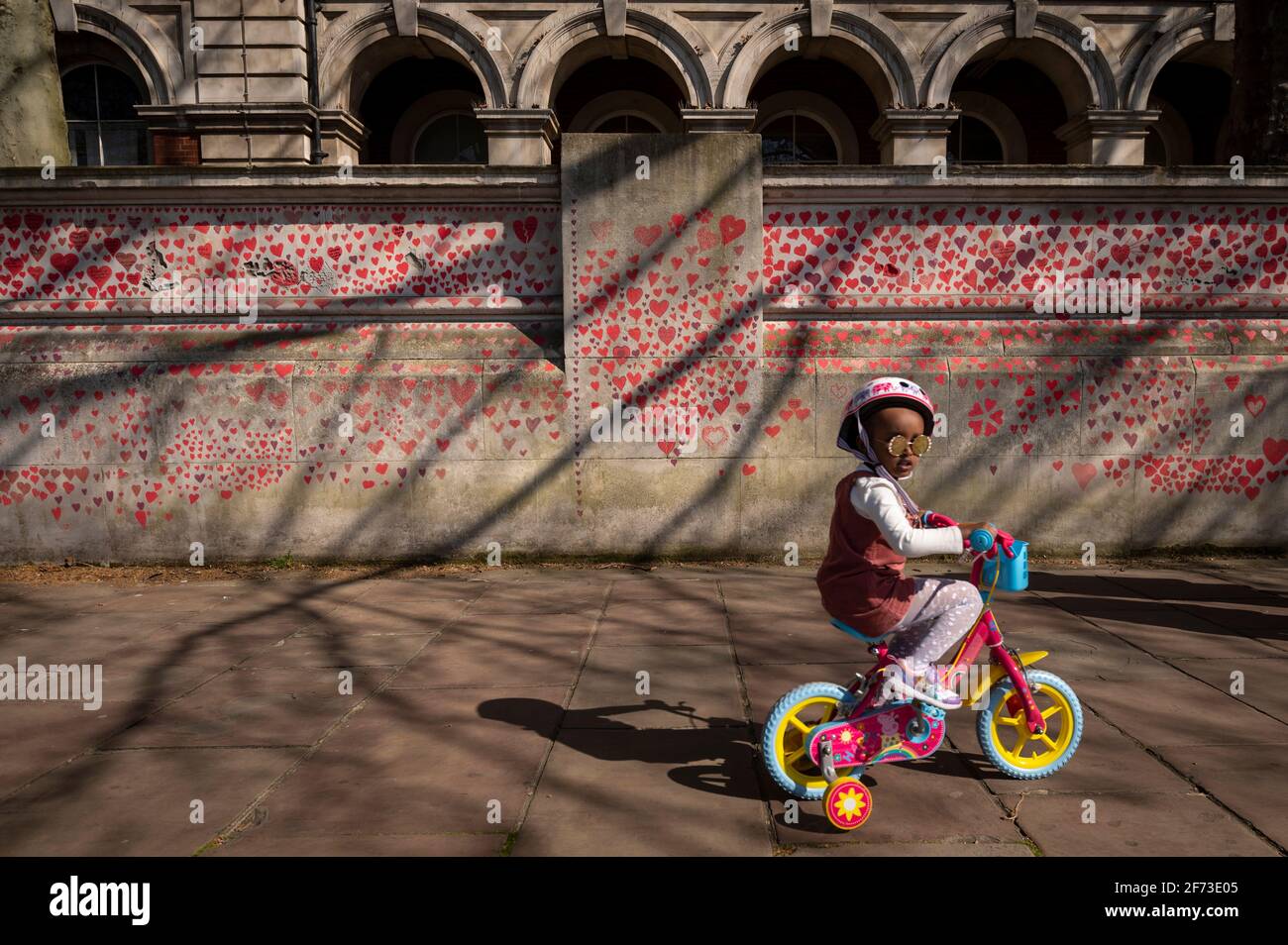 Londres, Royaume-Uni. 4 avril 2021. Un enfant à vélo passe les coeurs le dimanche de Pâques sur un mur à Lambeth près de la Tamise, chaque cœur représentant une personne décédée pendant la pandémie de coronavirus au Royaume-Uni. Appelé le mur commémoratif national Covid, il a été créé par le groupe Covid-19 Bereaved Families for Justice avec des travaux qui débutent il y a une semaine et s'étendra sur un demi-mile à la fin. Credit: Stephen Chung / Alamy Live News Banque D'Images