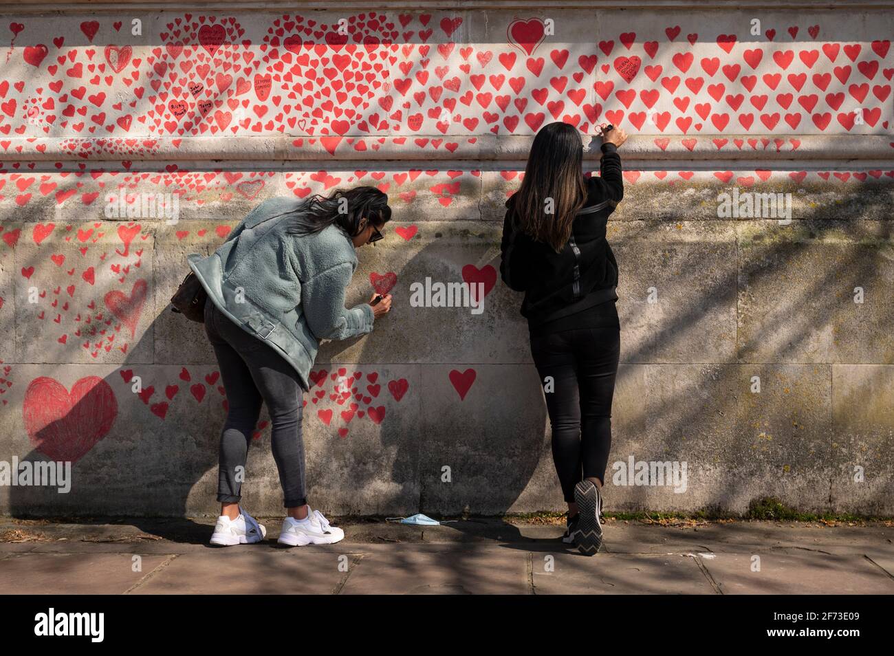 Londres, Royaume-Uni. 4 avril 2021. Les volontaires tirent le cœur le dimanche de Pâques sur un mur à Lambeth, près de la Tamise, chaque cœur représentant une personne décédée pendant la pandémie de coronavirus au Royaume-Uni. Appelé le mur commémoratif national Covid, il a été créé par le groupe Covid-19 Bereaved Families for Justice avec des travaux qui débutent il y a une semaine et s'étendra sur un demi-mile à la fin. Credit: Stephen Chung / Alamy Live News Banque D'Images