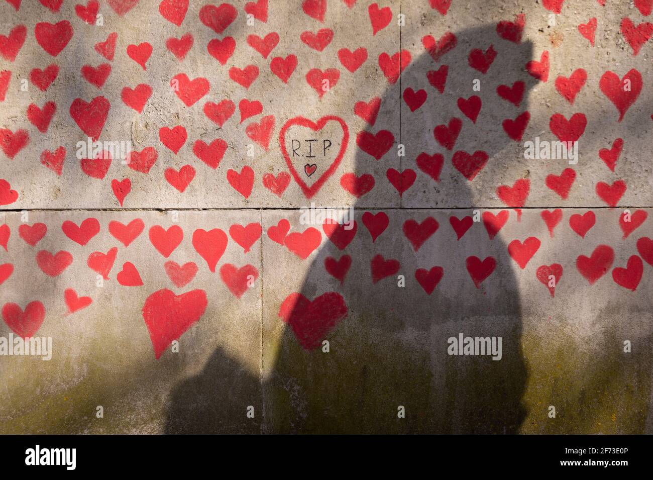 Londres, Royaume-Uni. 4 avril 2021. L'ombre et le cœur d'une personne le dimanche de Pâques sur un mur à Lambeth près de la Tamise, chaque cœur représentant une personne décédée pendant la pandémie de coronavirus au Royaume-Uni. Appelé le mur commémoratif national Covid, il a été créé par le groupe Covid-19 Bereaved Families for Justice avec des travaux qui débutent il y a une semaine et s'étendra sur un demi-mile à la fin. Credit: Stephen Chung / Alamy Live News Banque D'Images