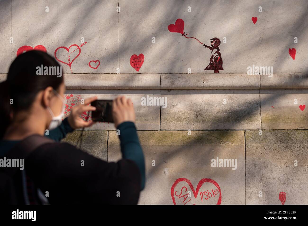 Londres, Royaume-Uni. 4 avril 2021. Le dimanche de Pâques, une femme voit un cœur inspiré par les Banksy sur un mur à Lambeth, près de la Tamise, chaque cœur représentant une personne décédée pendant la pandémie de coronavirus au Royaume-Uni. Appelé le mur commémoratif national Covid, il a été créé par le groupe Covid-19 Bereaved Families for Justice avec des travaux qui débutent il y a une semaine et s'étendra sur un demi-mile à la fin. Credit: Stephen Chung / Alamy Live News Banque D'Images