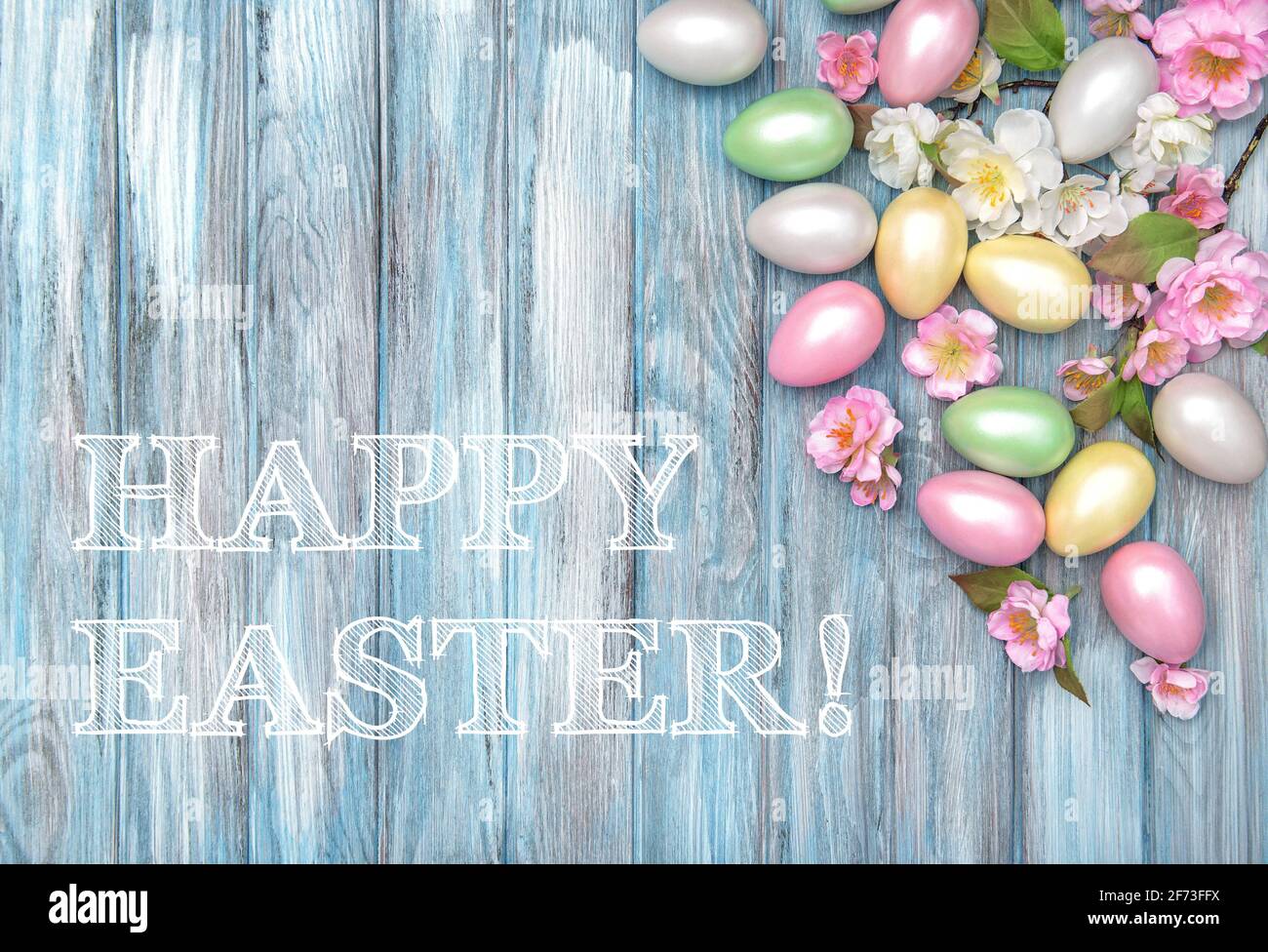 Joyeuses Pâques ! Œufs de Pâques et fleurs de printemps sur fond bleu en bois Banque D'Images