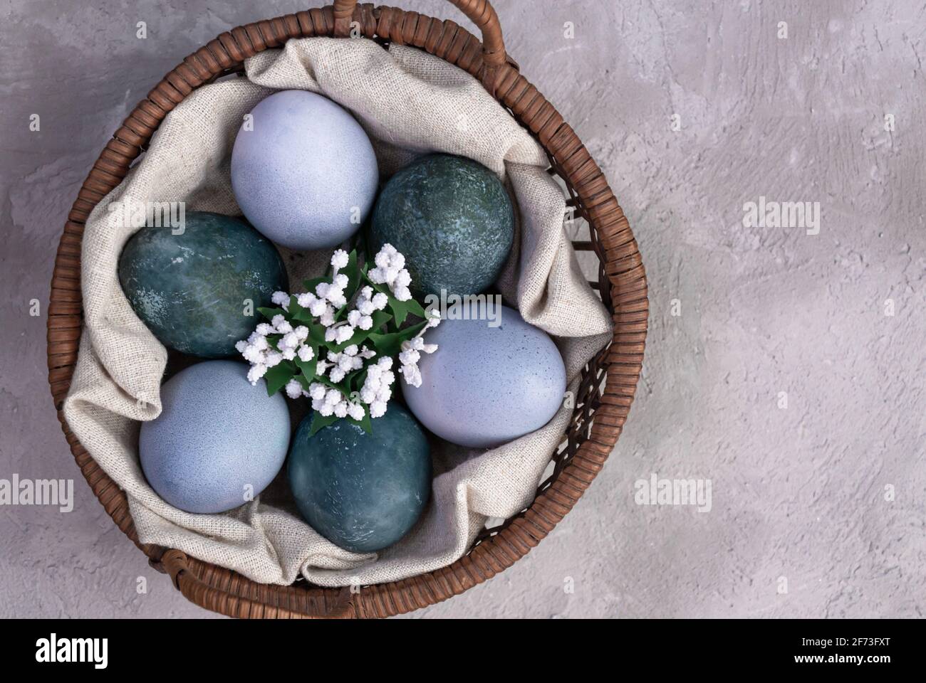 Les oeufs de Pâques dans un panier de fleurs artificielles sont peints avec des teintures naturelles. Thé Hibiscus et chou rouge Banque D'Images