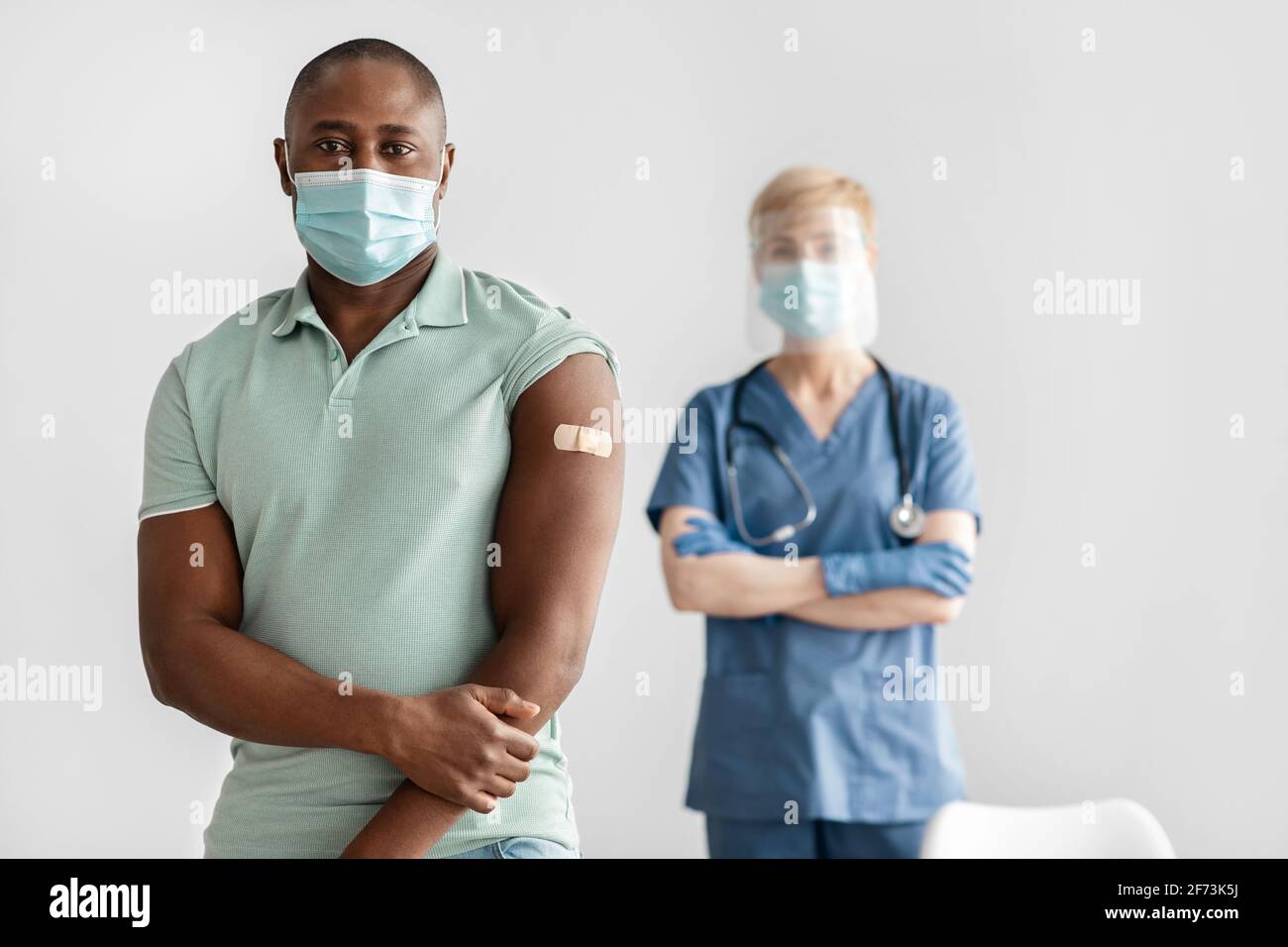Femme mature infirmière ou médecin en uniforme, masque protecteur tient avec le patient afro-américain millénaire Banque D'Images
