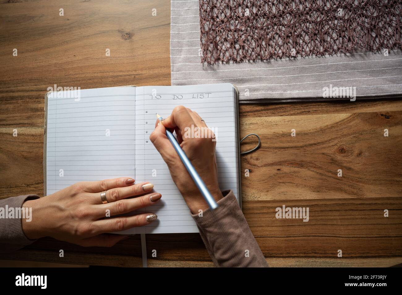 Vue de dessus des mains de femmes écrivant une liste de tâches dans le carnet à la maison. Banque D'Images
