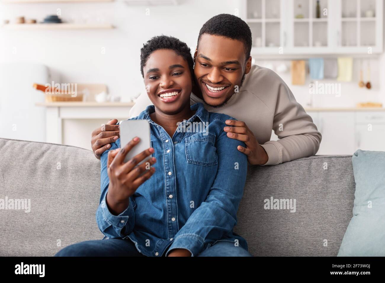 Couple noir assis sur un canapé, à l'aide d'un smartphone Photo Stock -  Alamy