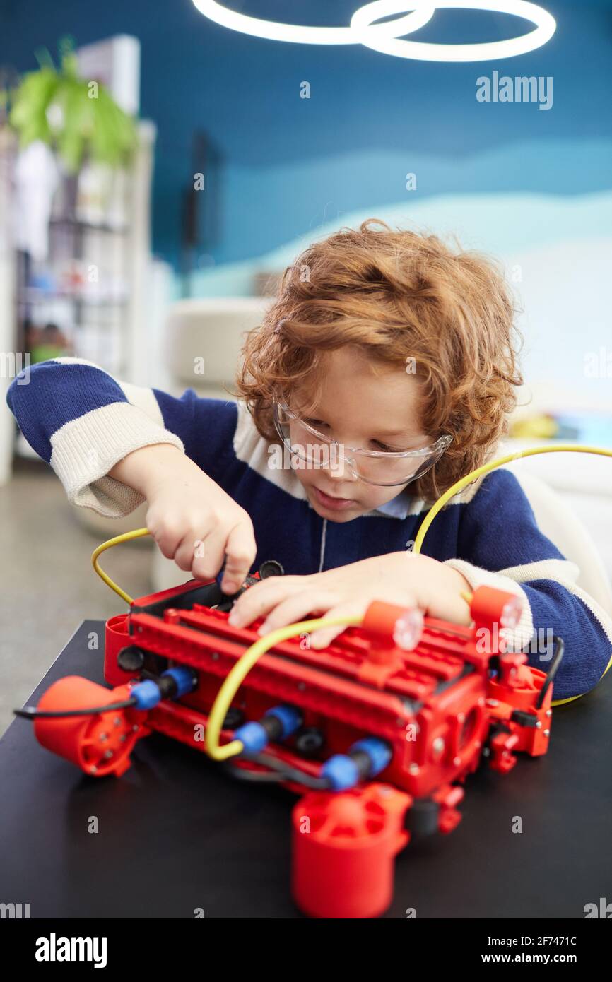 Portrait vertical du robot de construction de garçon mignon pendant la classe d'ingénierie dans l'école de développement Banque D'Images