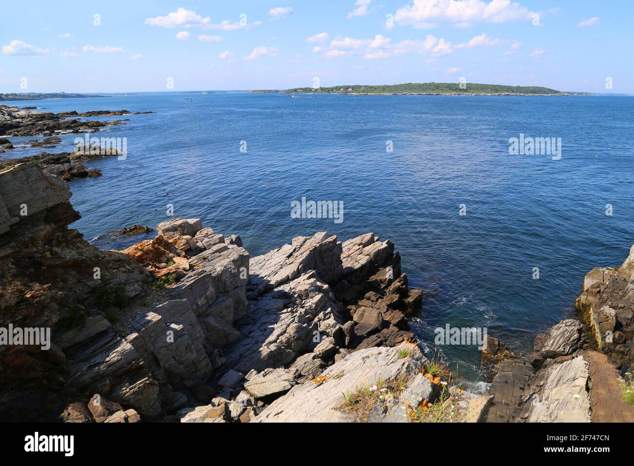 Ocean Bay depuis le haut, au sommet d'une falaise avec rebord de roche, ciel bleu, nuages légers et une île à l'horizon Banque D'Images