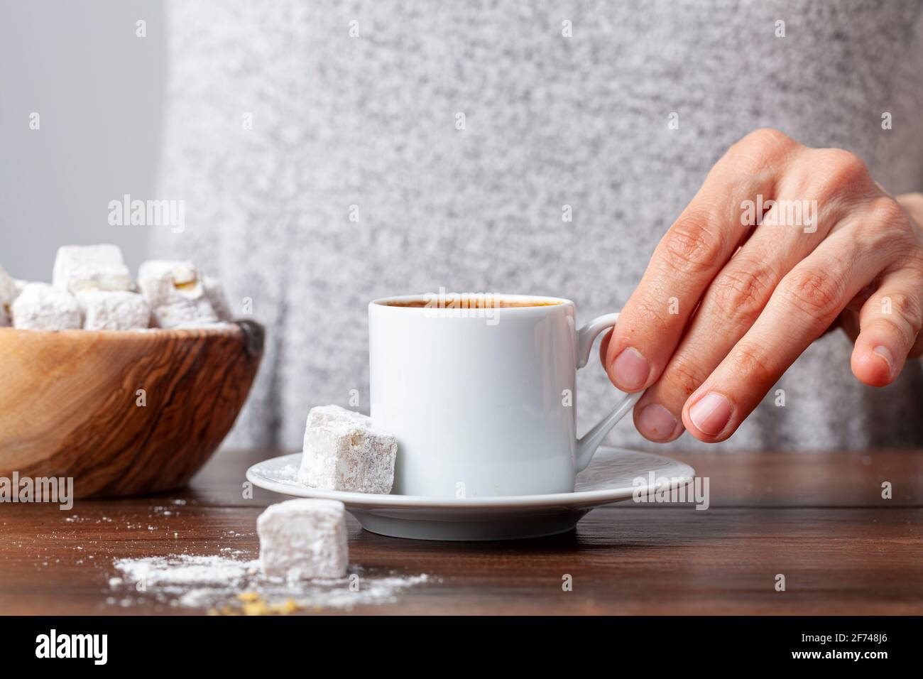 Une femme turque de race blanche boit du café turc traditionnel dans une tasse spéciale. Le café est servi avec un délice turc sur le côté de l'assiette Banque D'Images