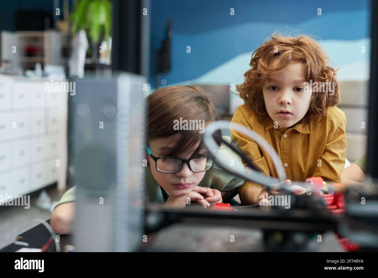 Portrait de deux écoliers regardant une imprimante 3D pendant un cours d'ingénierie à l'école moderne, espace de copie Banque D'Images
