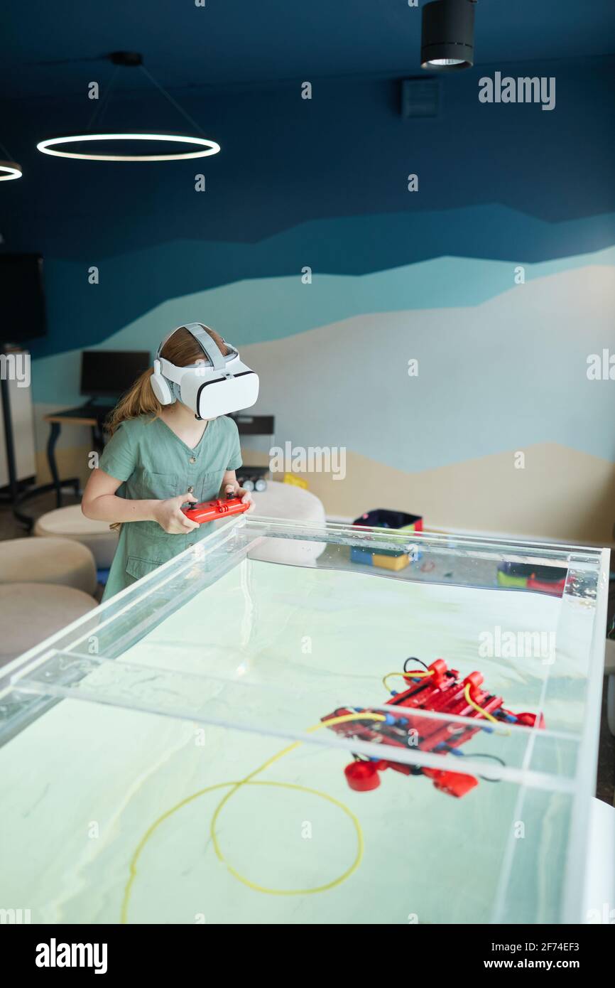 Portrait vertical d'un enfant portant un casque VR tout en utilisant un bateau robotique dans un laboratoire scolaire, espace de copie Banque D'Images