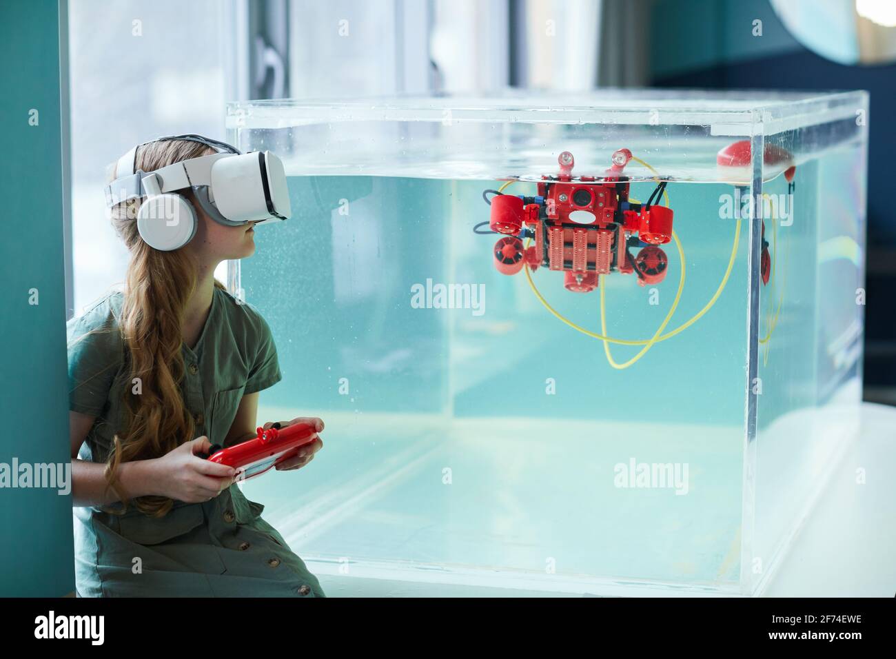 Vue latérale d'une fille portant un casque VR tout en utilisant un bateau robotique dans un laboratoire scolaire, espace de copie Banque D'Images