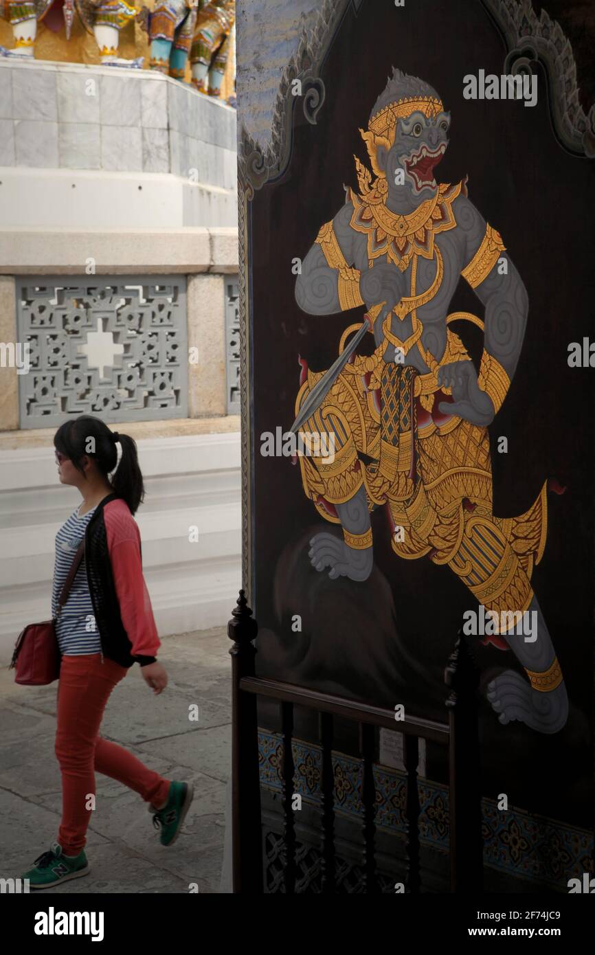 Un visiteur passant devant une entrée décorée d'une peinture murale, faisant partie d'une galerie de peintures murales représentant Ramakien (version thaï de l'épopée de Ramayana) qui est situé au Wat Phra Kaew (Temple du Bouddha d'Émeraude), à l'intérieur du complexe du Grand Palais à Bangkok, en Thaïlande. La Thaïlande est le premier pays d'Asie du Sud-est à réduire les restrictions de quarantaine (de 14 à 10 jours) pour accélérer la reprise de son secteur touristique, selon le South China Morning Post on 2 avril 2021. La décision a été prise d'accélérer le processus de récupération, qui devait être un « retour lent ». Banque D'Images