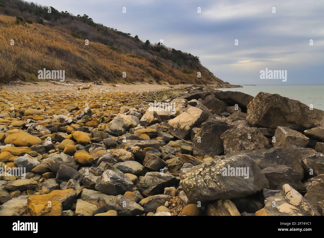 Vue sur la plage en pierres sombres au premier plan en hiver. Pesaro, région des Marches, Italie Banque D'Images