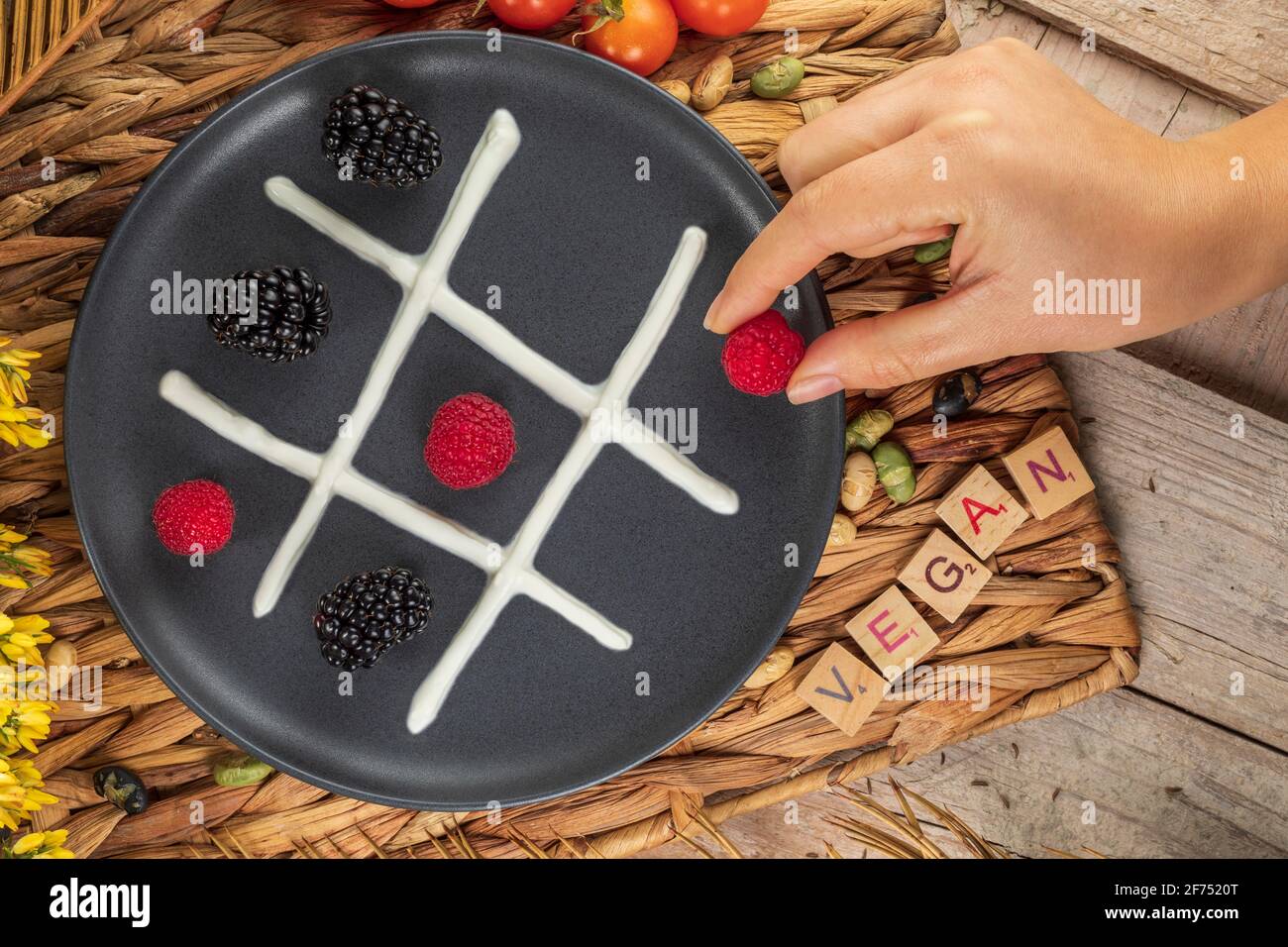 Vue de dessus de la récolte non reconnaissable cuire en mettant la framboise entière sur assiette avec des mûres et de la crème fouettée représentant les oughts et les croix jeu Banque D'Images
