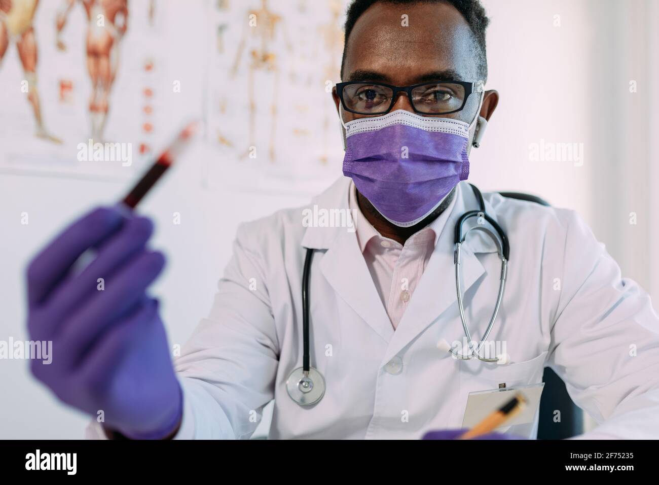 Afro-américain médecin en gant médical démontrant tube à essai avec échantillon de sang sur fond blanc Banque D'Images