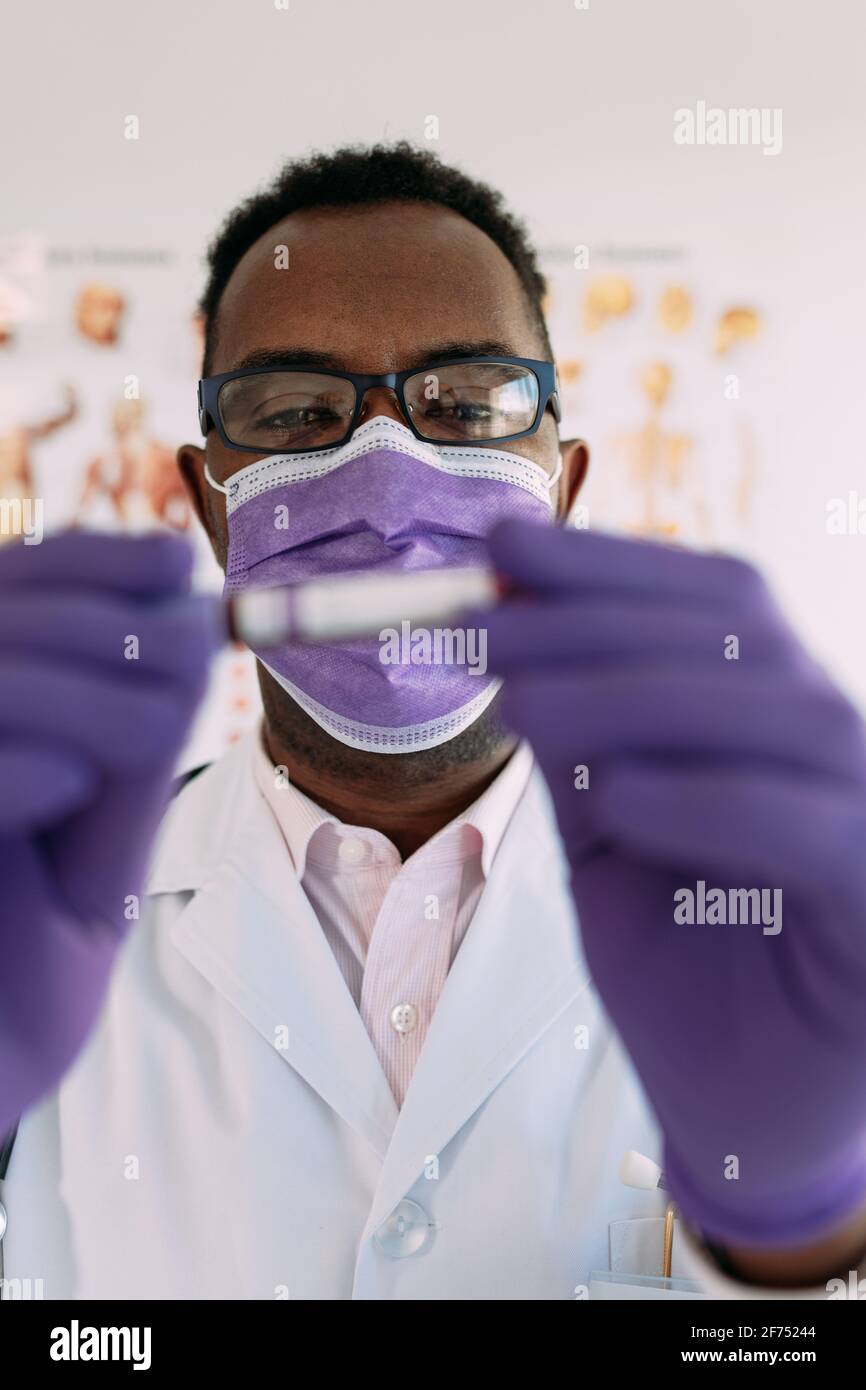 Afro-américain médecin en gant médical démontrant tube à essai avec échantillon de sang sur fond blanc Banque D'Images