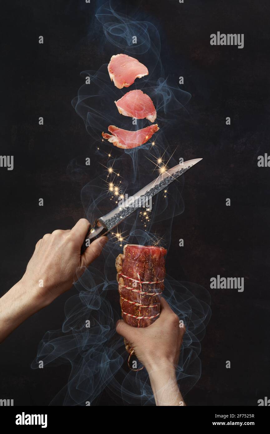 Main mâle avec couteau coupant du jambon de bœuf fumé Banque D'Images