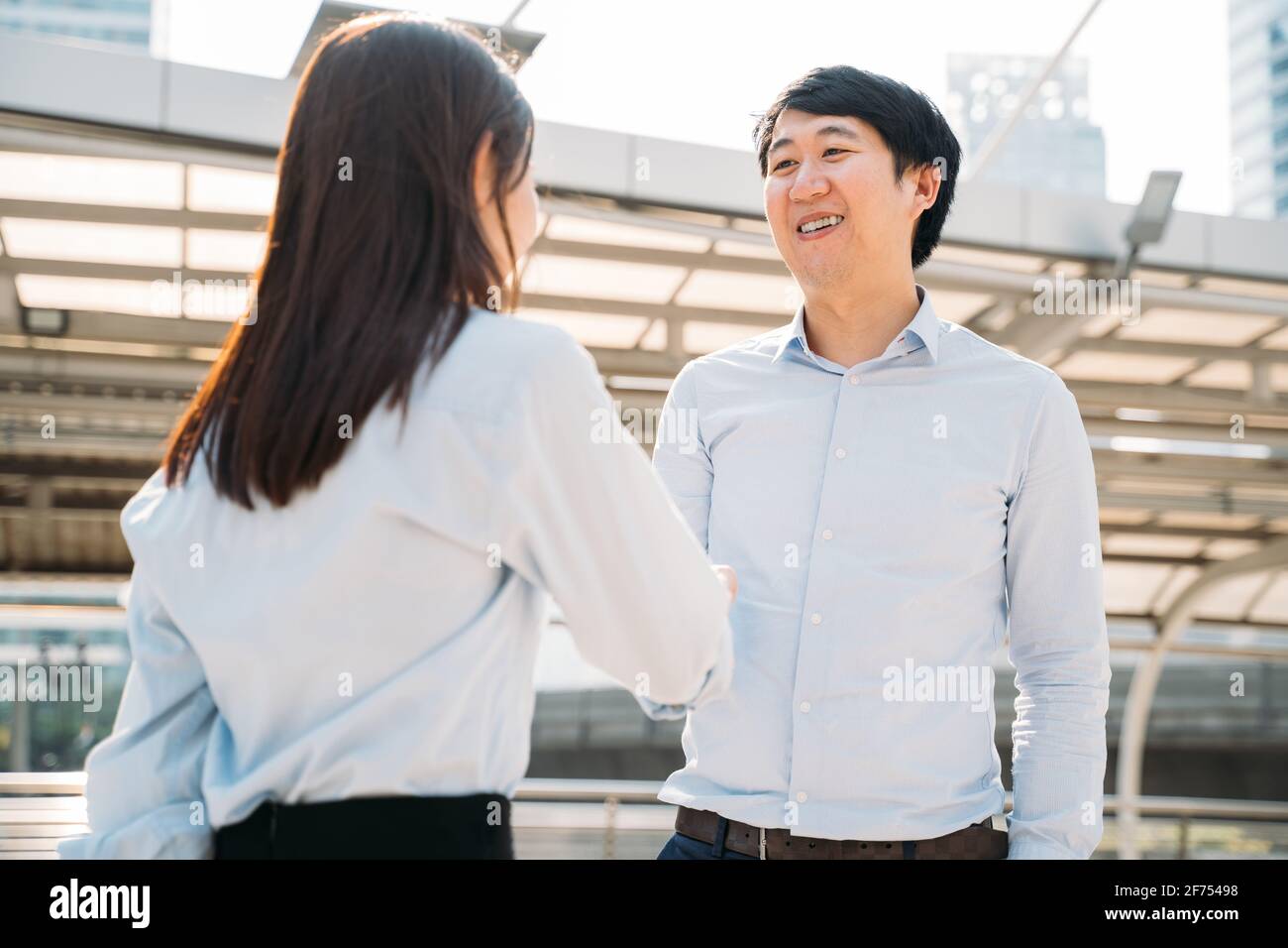 Portrait d'un jeune homme d'affaires asiatique souriant qui se tremble entre les mains une jeune femme employée à l'extérieur du bureau après avoir été sélectionnée pour tâche Banque D'Images