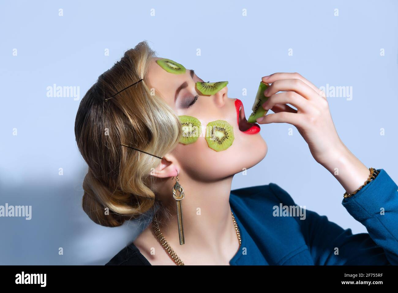 Photo de mode de la femme posant avec des tranches de kiwi son visage Banque D'Images