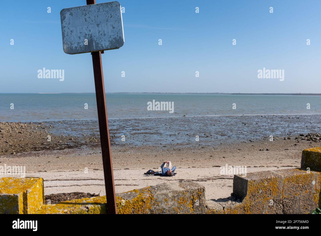 ARS-en-Ré, France - 24 février 2020 : une personne envoie un SMS sur une plage prise de loin sur l'île de Ré par un beau jour de fin d'hiver Banque D'Images