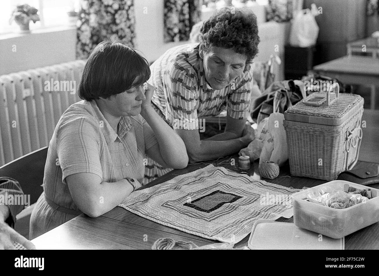 Strode Park un centre de jour pour les handicapés physiques et mentaux. Un soignant aide une femme avec son embroderie Banque D'Images