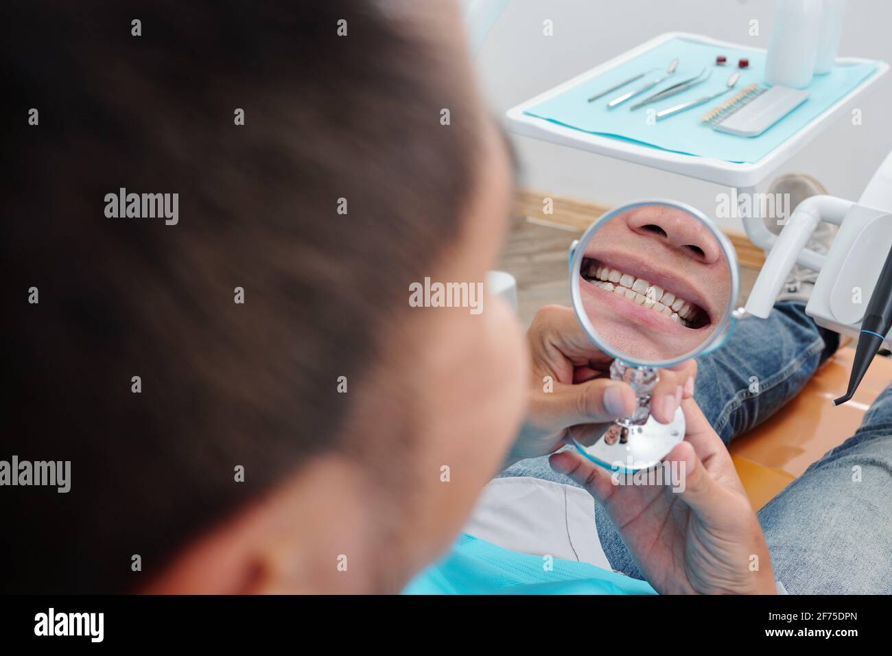 Gros plan de l'homme avec petit miroir souriant à ses dents droites traitées Banque D'Images