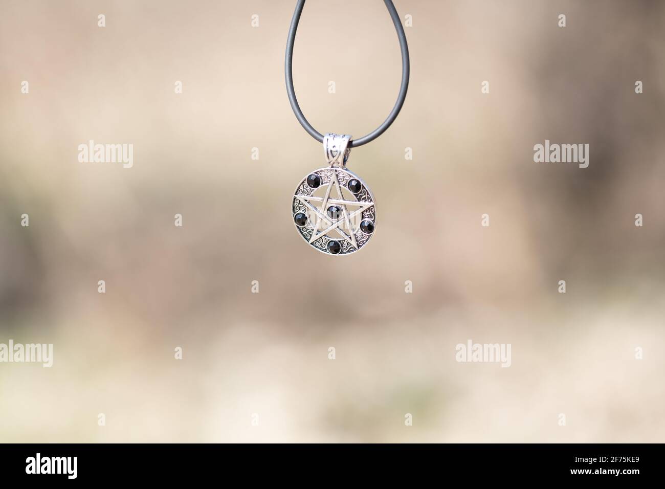 Pendentif Magic Pentagram collier argent et noir acier inoxydable tirer dehors dans un jour d'été gros plan. Banque D'Images