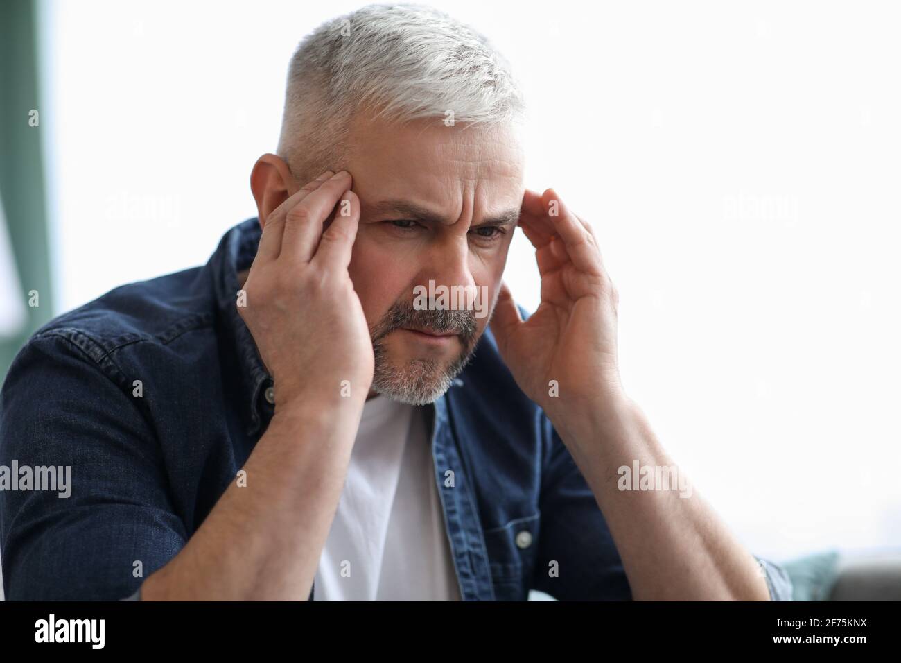 Gros plan de l'homme mature à cheveux gris souffrant de migraine Banque D'Images