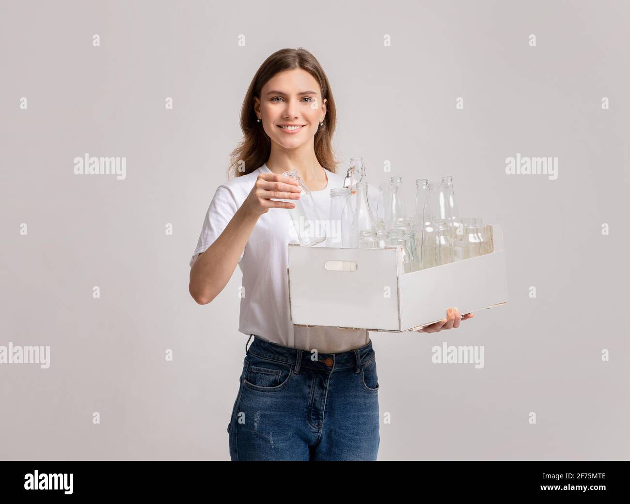 Réutilisation des déchets. Femme souriante tenant une boîte avec des bouteilles en verre vides Banque D'Images