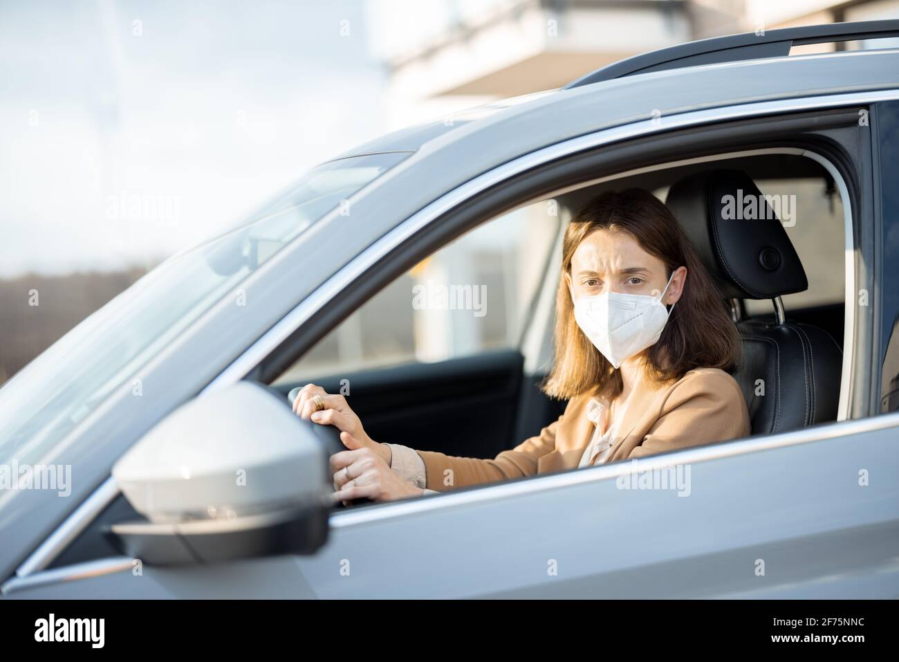 Jeune femme conduisant une voiture avec un masque de protection sur son visage. Je m'inquiète de l'appareil photo. Santé, protection contre les virus, concept de protection contre les allergies. Banque D'Images